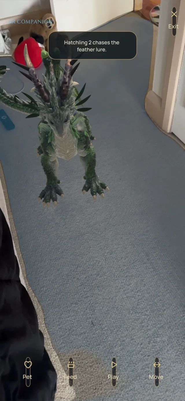 Captured on iPhone: a green dragon standing on a real carpeted hallway floor in AR, chasing a feather lure